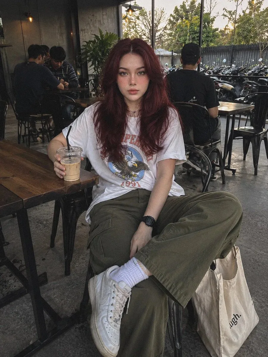 Red-haired woman seated with an iced drink in a cafe